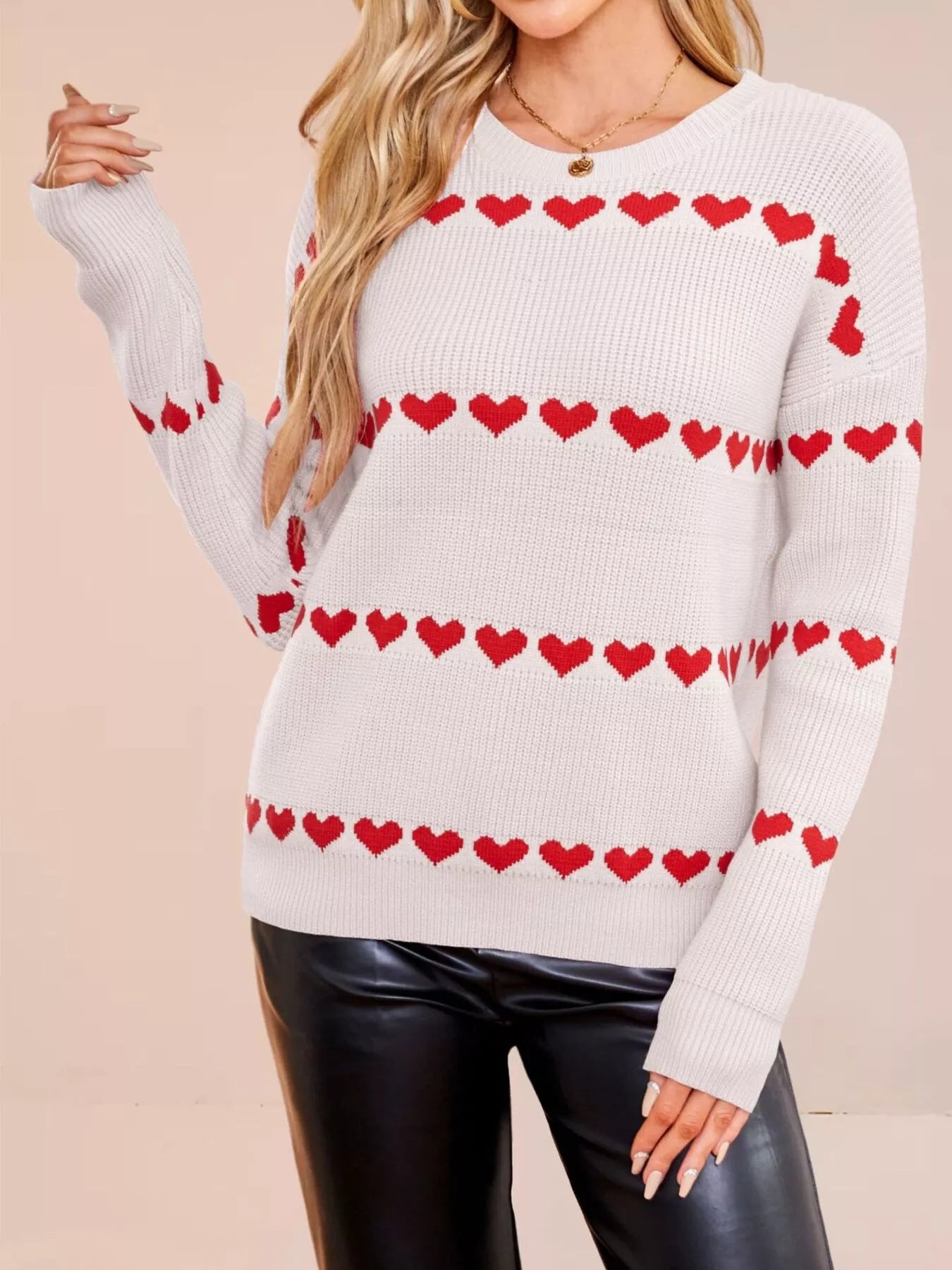 On-model front view of a white dropped shoulder sweater with red heart stripes, arm raised