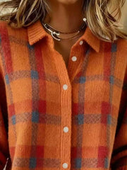 Close-up of the collar and button placket on an orange and red plaid knit cardigan