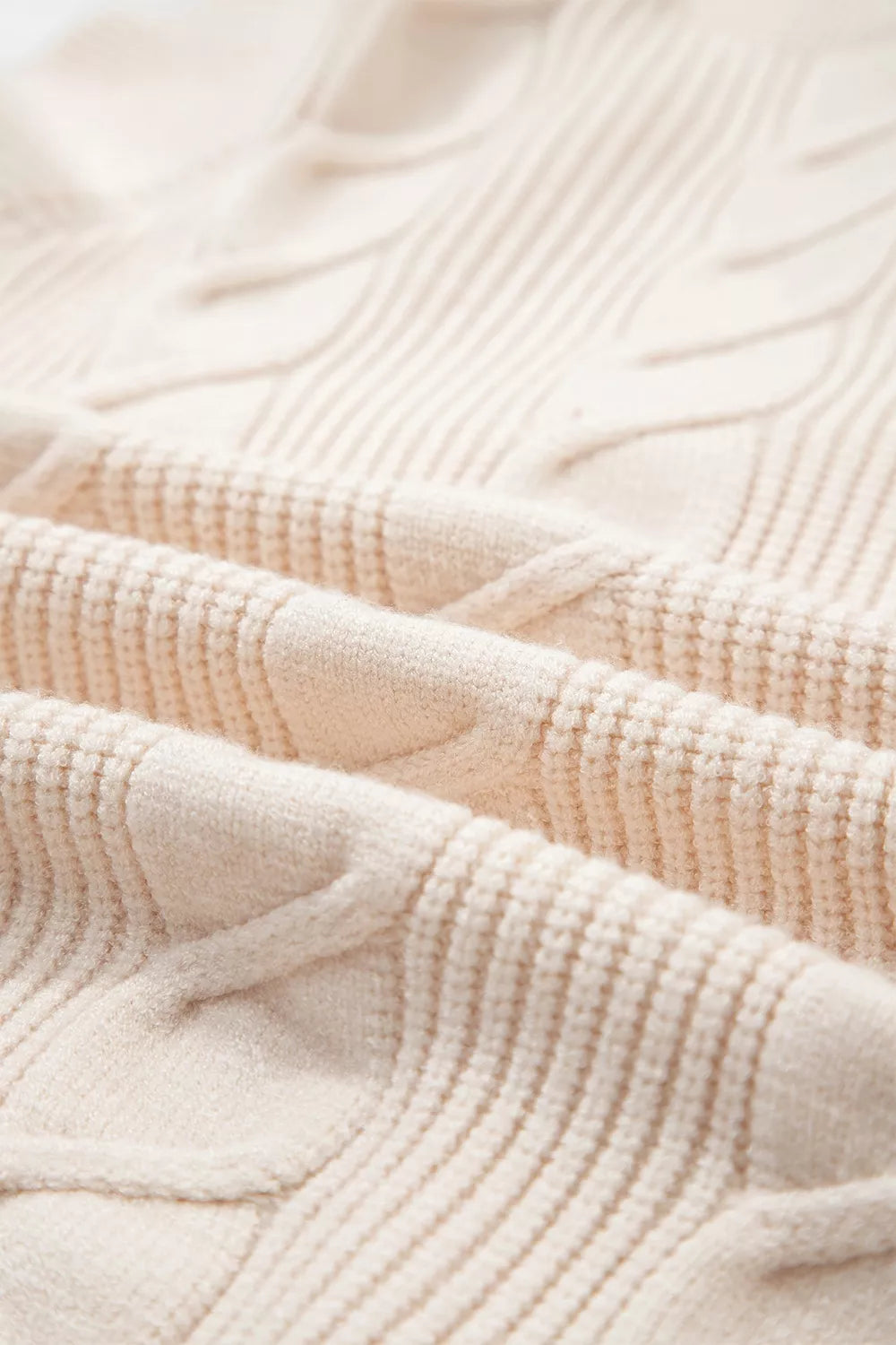 Close-up detail of cream cable knit fabric with a twisted texture