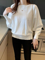 Front view of the white batwing sleeve knit top with vertical seams, worn indoors with a chain bag.