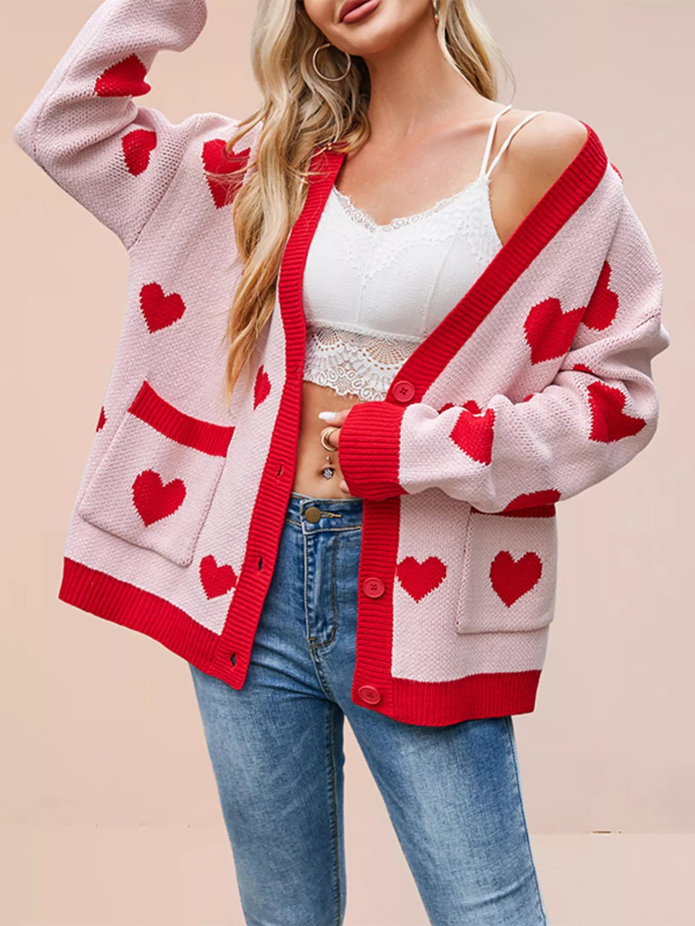 Pink knit cardigan with red hearts and red trim worn open off shoulder