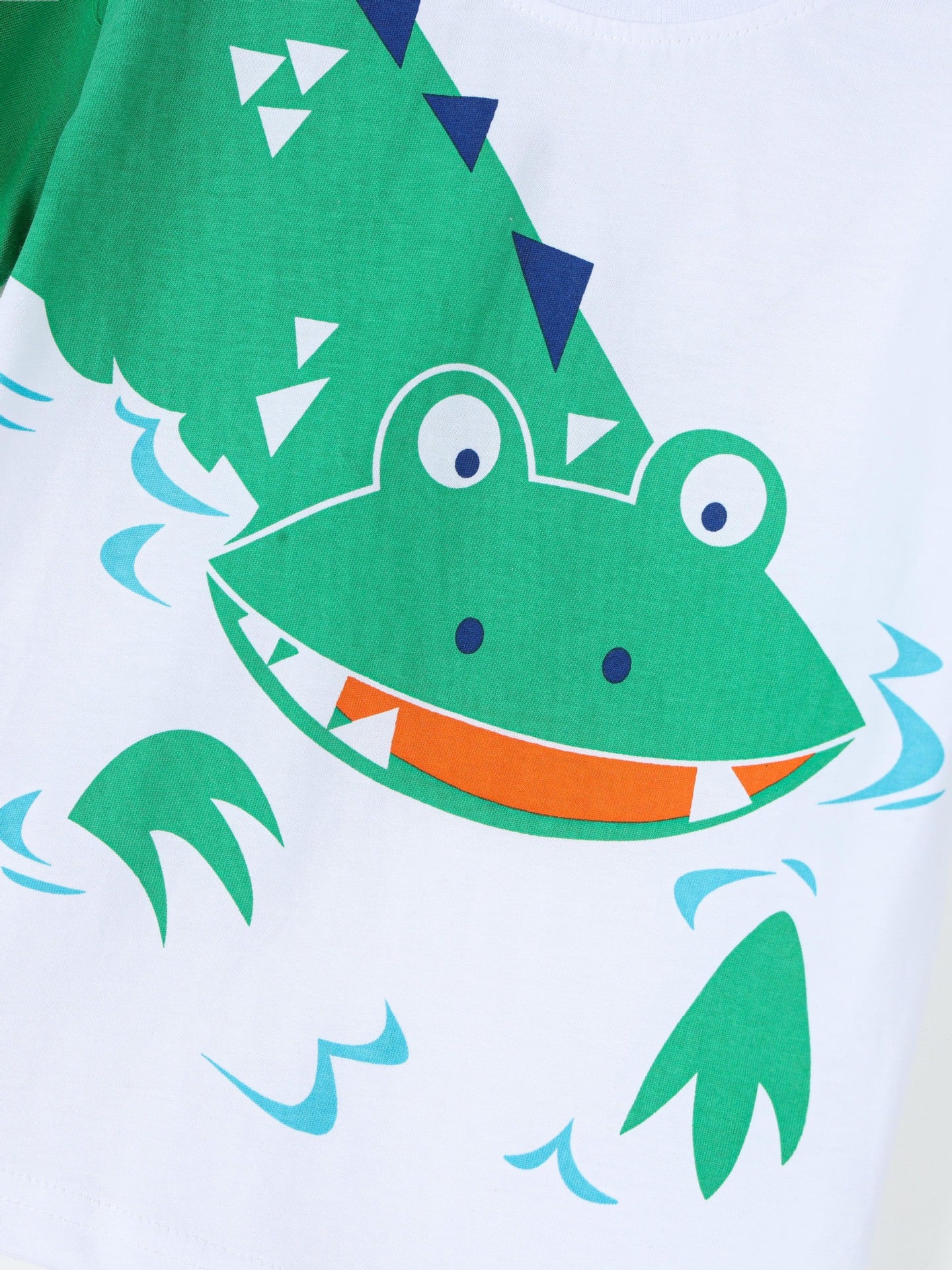 Close view of the green crocodile face graphic with orange mouth on white fabric