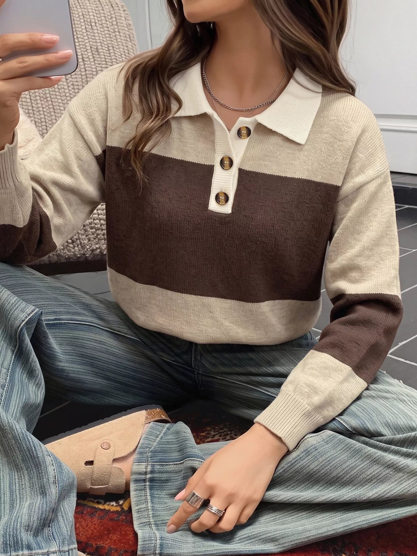 Seated front view of beige and brown color block polo sweater with cream collar.