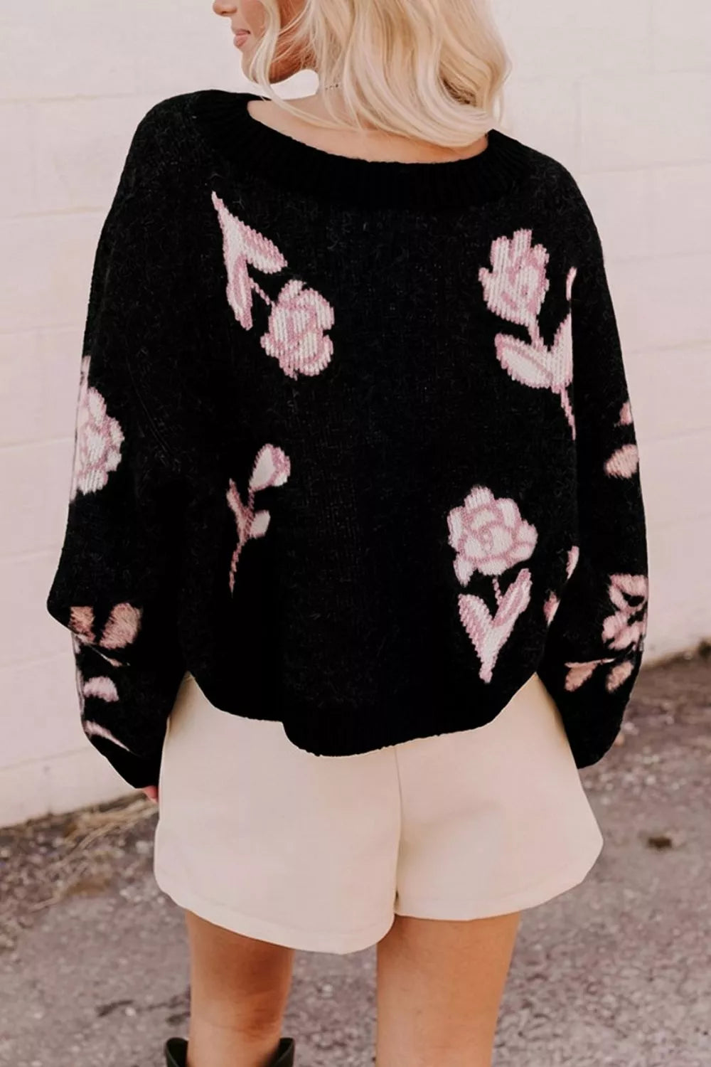 Back view of black floral pullover sweater with pink roses, worn with light shorts