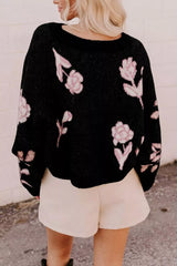 Back view of black floral pullover sweater with pink roses, worn with light shorts