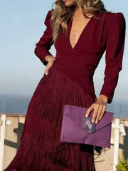 Close front view of a burgundy fringed maxi dress with a tiered fringe skirt