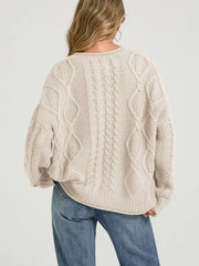 Back view of cream cable knit cardigan with diamond cable pattern and blue jeans