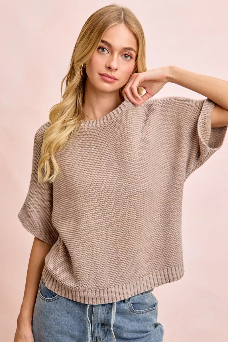 Front view of washed mocha dolman knit top with hand resting near neckline.