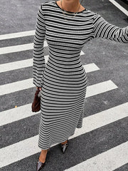 On-model front view of the black and white striped sweater dress with one arm extended