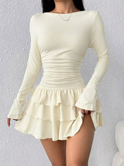 Apricot long sleeve mini dress worn front facing while holding the tiered ruffle skirt