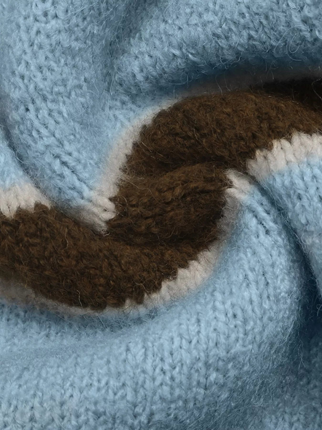 Close up of soft blue and brown striped knit texture with cream edging.