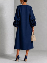 Back view of the navy round neck midi dress with balloon sleeves and large floral sleeve cuffs