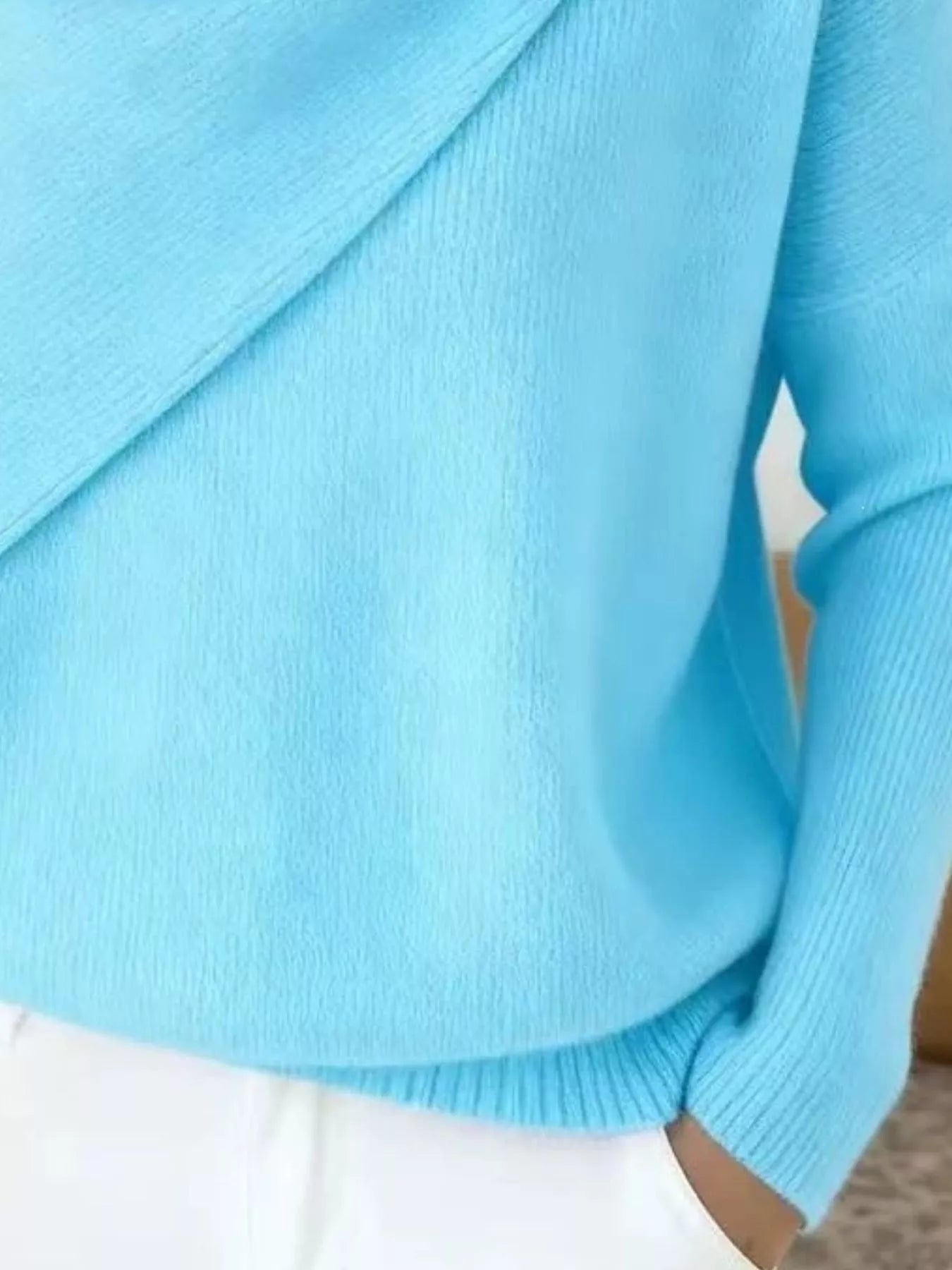 Close-up of the light blue sweater lower body and long sleeve showing the ribbed hem and knit texture