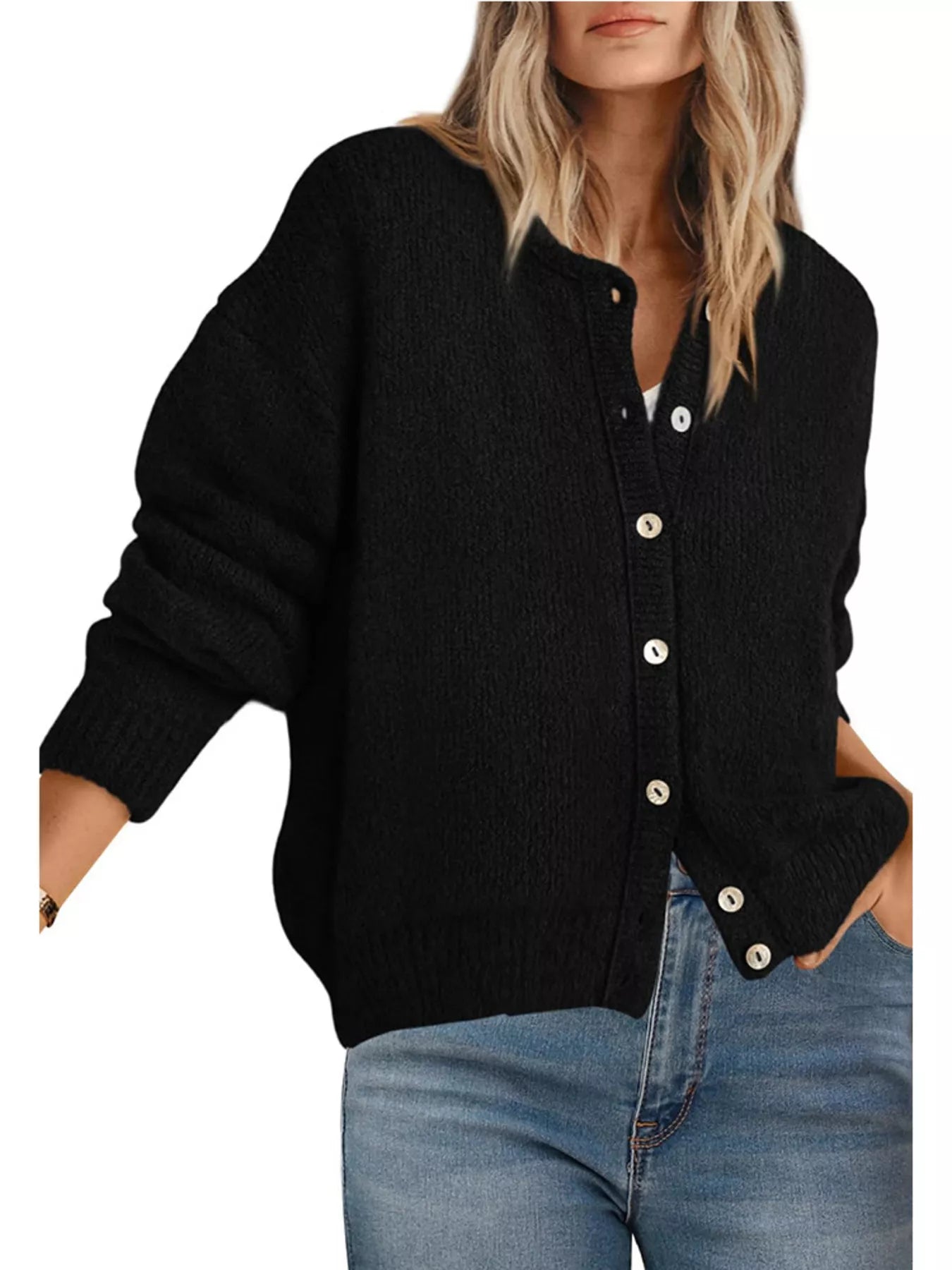 Front view of black button down cardigan with white buttons worn with blue jeans