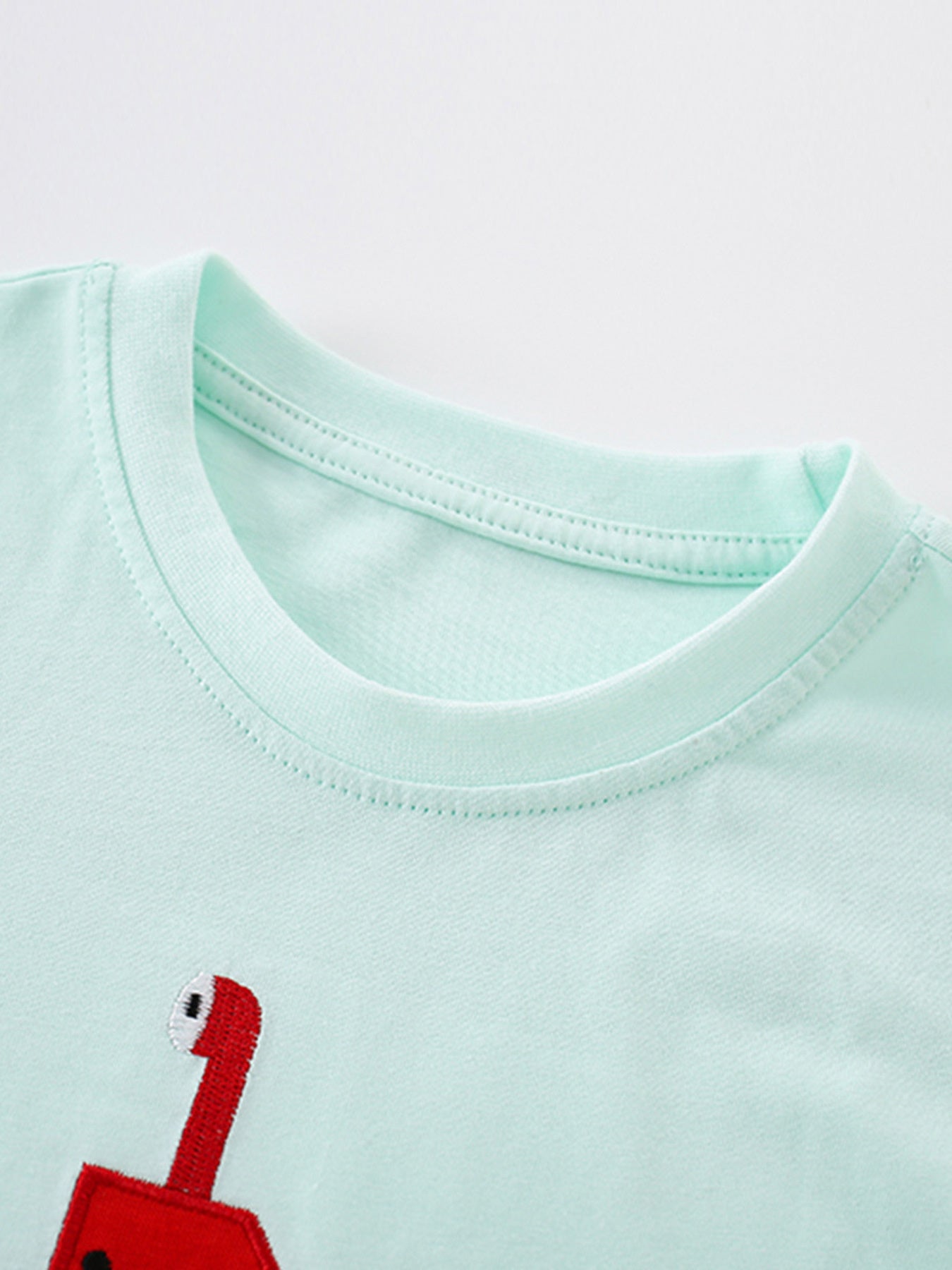 Close view of the mint children's tee neckline showing neat ribbed stitching and soft fabric