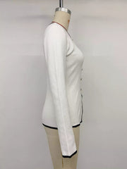 Side view of white knit top on a mannequin, showing long sleeves and black trim.