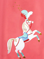 Close-up of white cartoon horse graphic with feathered headdress and gold stars on coral t-shirt