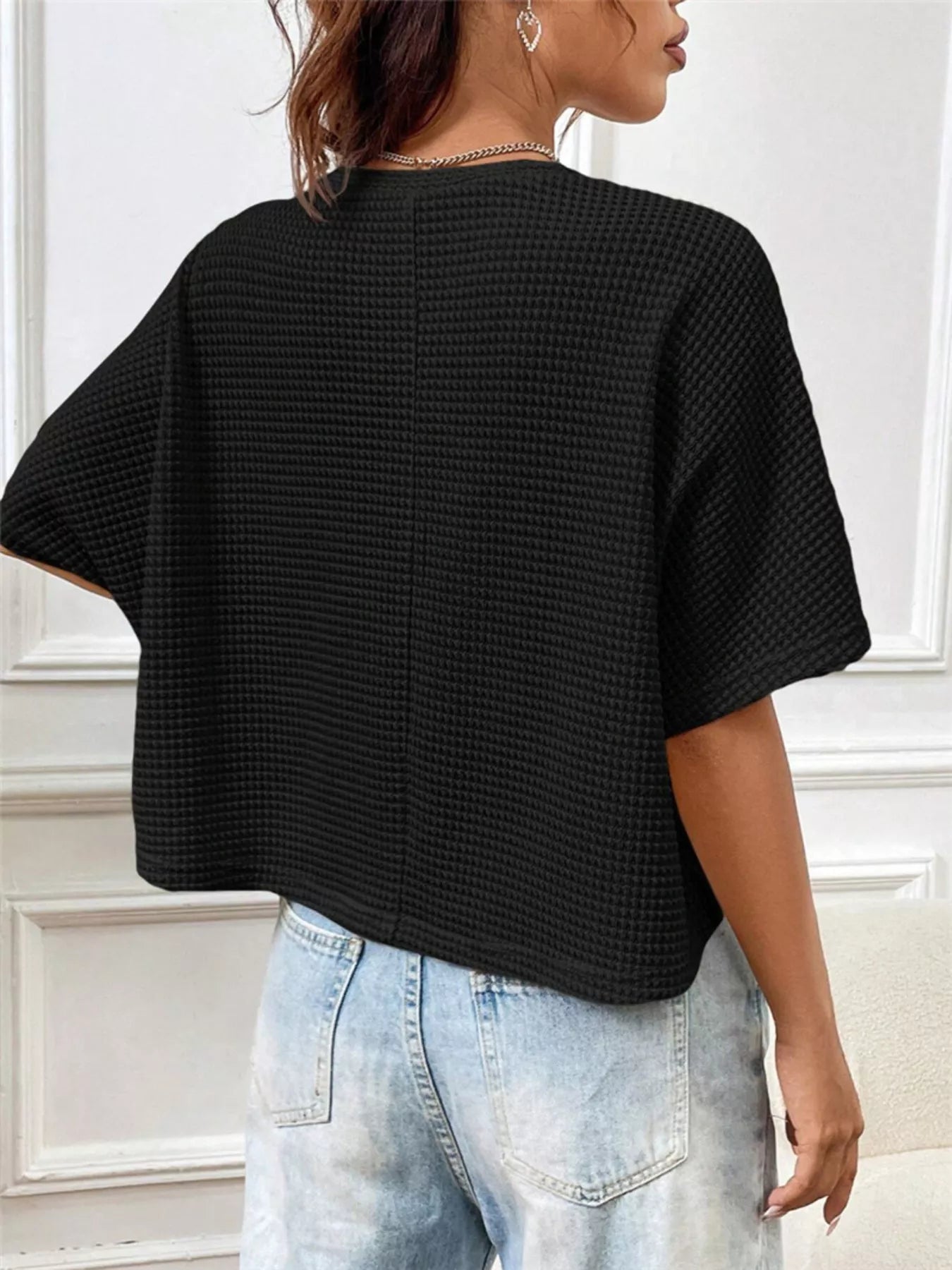 Back view of black waffle-knit cropped T-shirt with short sleeves and relaxed fit