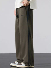 Men's army green striped wide-leg sweatpants with a drawstring waist and pockets.