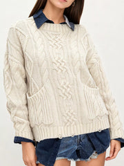 Front view of ivory cable knit sweater with front pockets layered over denim and shorts