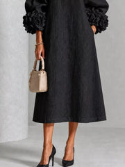 Lower front view of the black round neck midi dress skirt with floral cuffs and loose fit