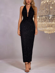 Black glitter halter neck bodycon maxi dress worn full length facing forward beside a chandelier