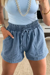 Women's denim shorts with a smocked elastic waist, drawstring, and pockets.