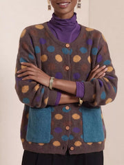 Front view of coffee brown polka dot cardigan with arms crossed and teal pockets