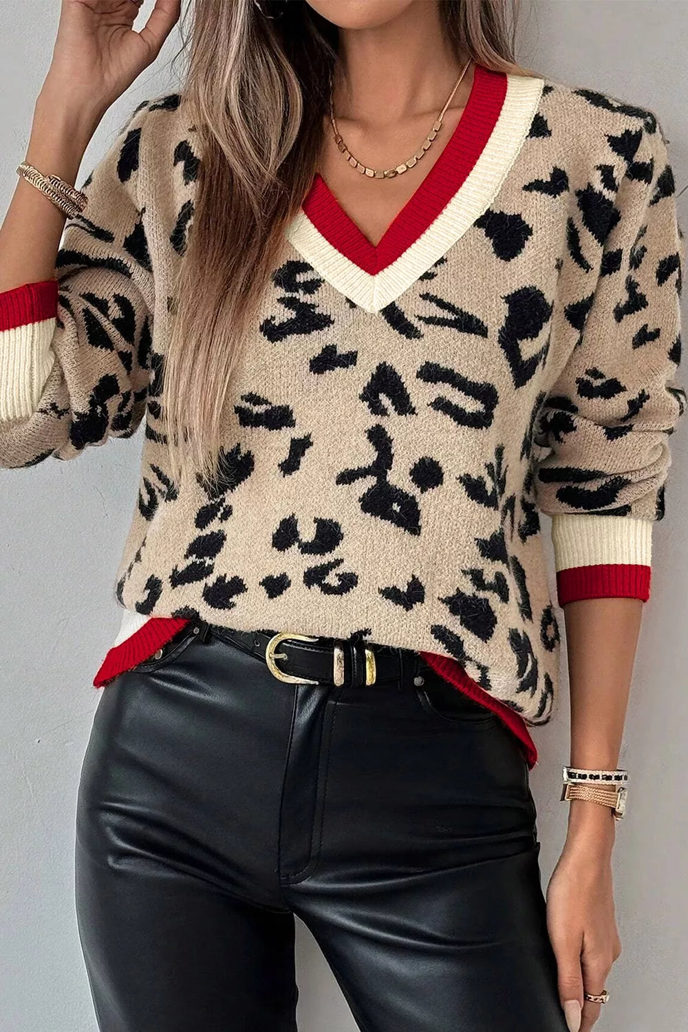 Front view of beige leopard print knit sweater with red and cream V neck trim.