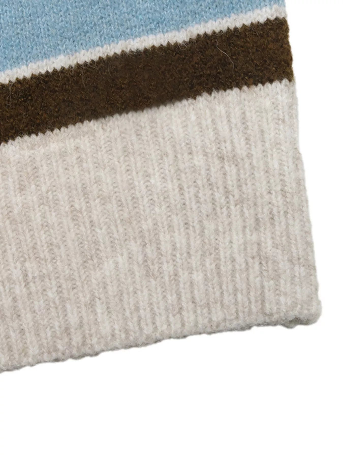 Close up of cream ribbed hem below blue and brown striped knit fabric.