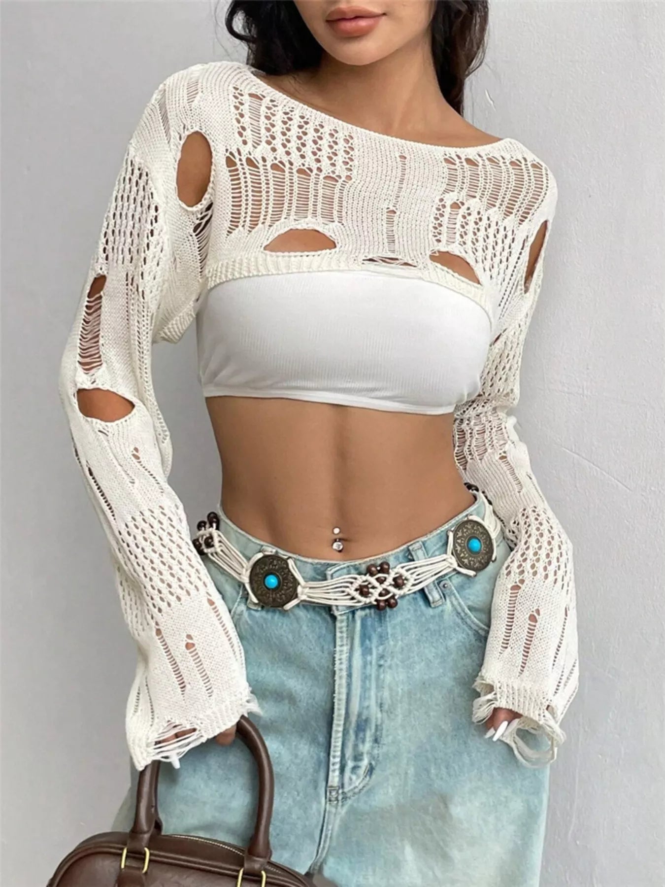 Front view of cream distressed cropped knit cover up with openwork and cutouts.
