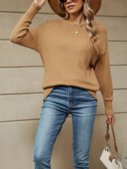Front view of a camel dropped shoulder knit sweater with a ribbed neckline and jeans