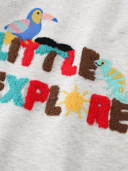 Close view of the textured Little Explorer lettering with toucan, chameleon and sun details