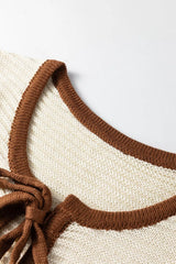 Close up front detail of a beige sweater vest neckline with brown contrast trim