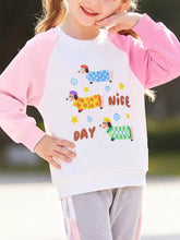 White children's sweatshirt with pink raglan sleeves shown worn outdoors featuring three cartoon dachshunds