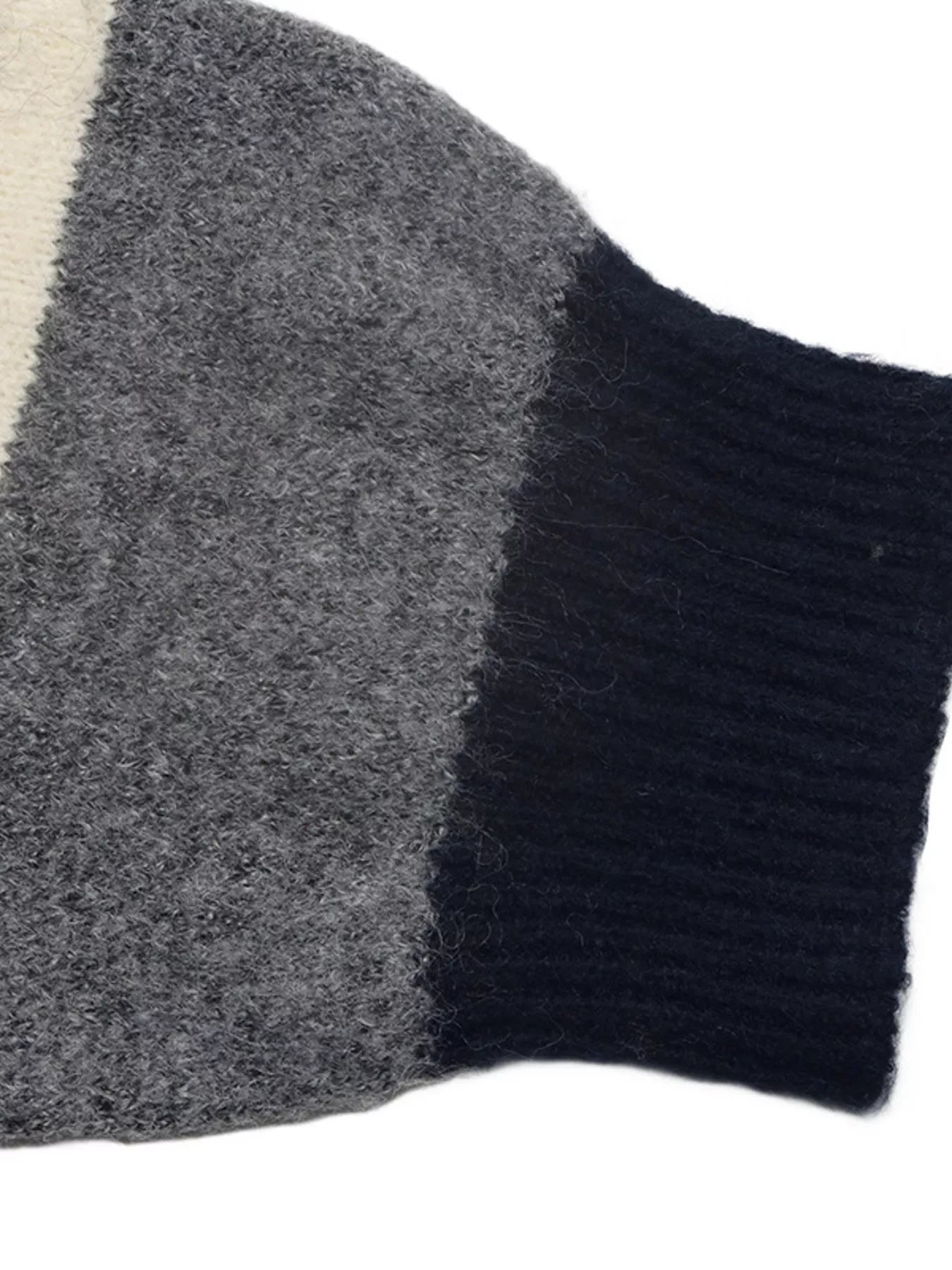 Close-up of the striped sweater sleeve with its gray knit and navy ribbed cuff