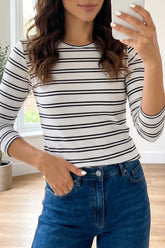 Front view of a white ribbed knit top with black horizontal stripes and long sleeves