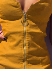 Close up detail of mustard yellow zip front bodycon mini dress showing ring zip pull and bodice seams