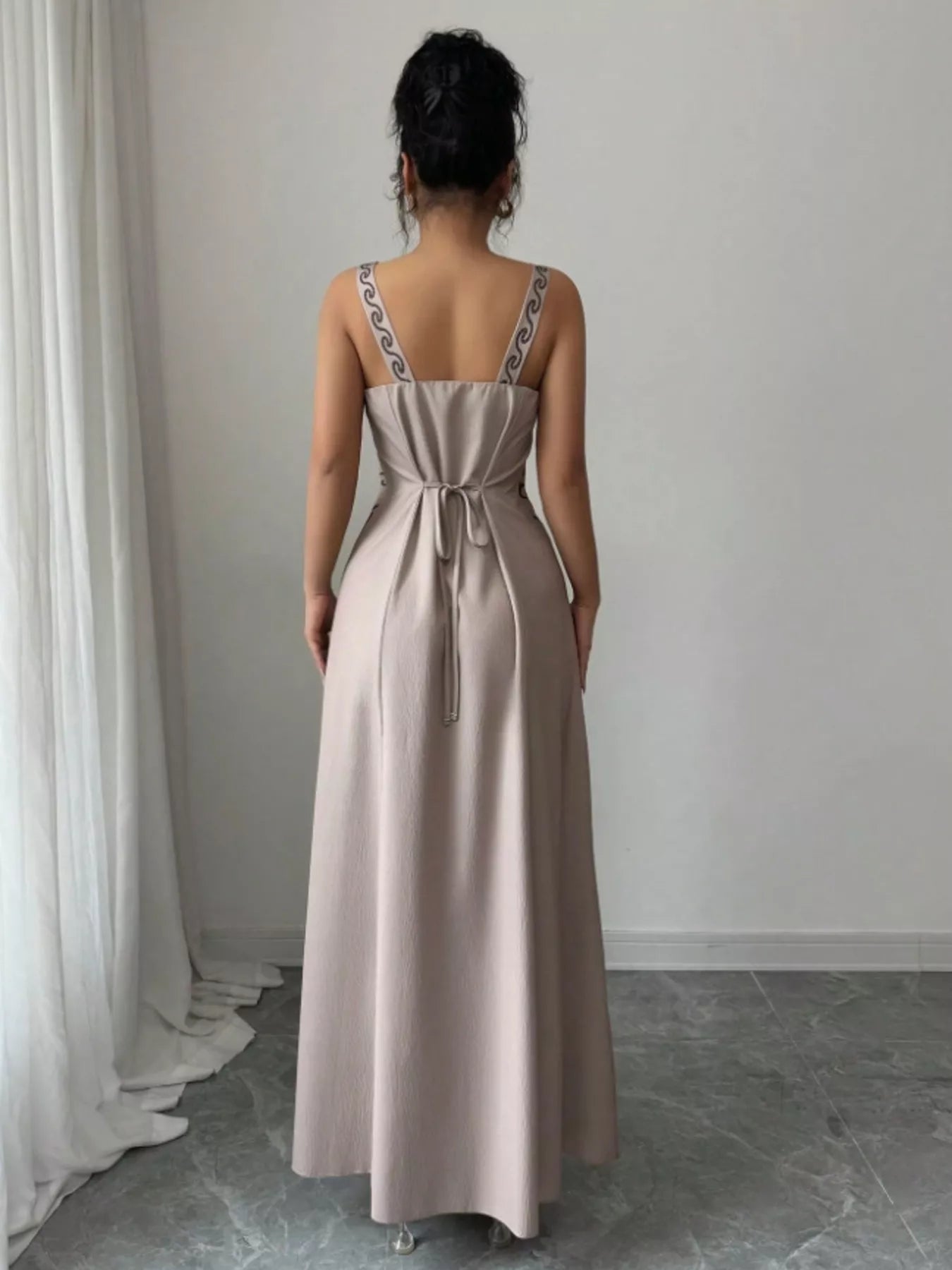 Back view of gray sleeveless maxi dress with tied waist and patterned straps