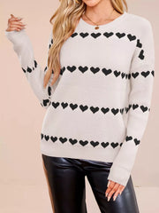 On-model front view of a white dropped shoulder sweater with rows of black hearts
