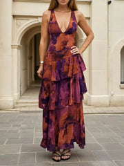 Front view of a deep purple floral V neck maxi dress with layered ruffles on a model outdoors