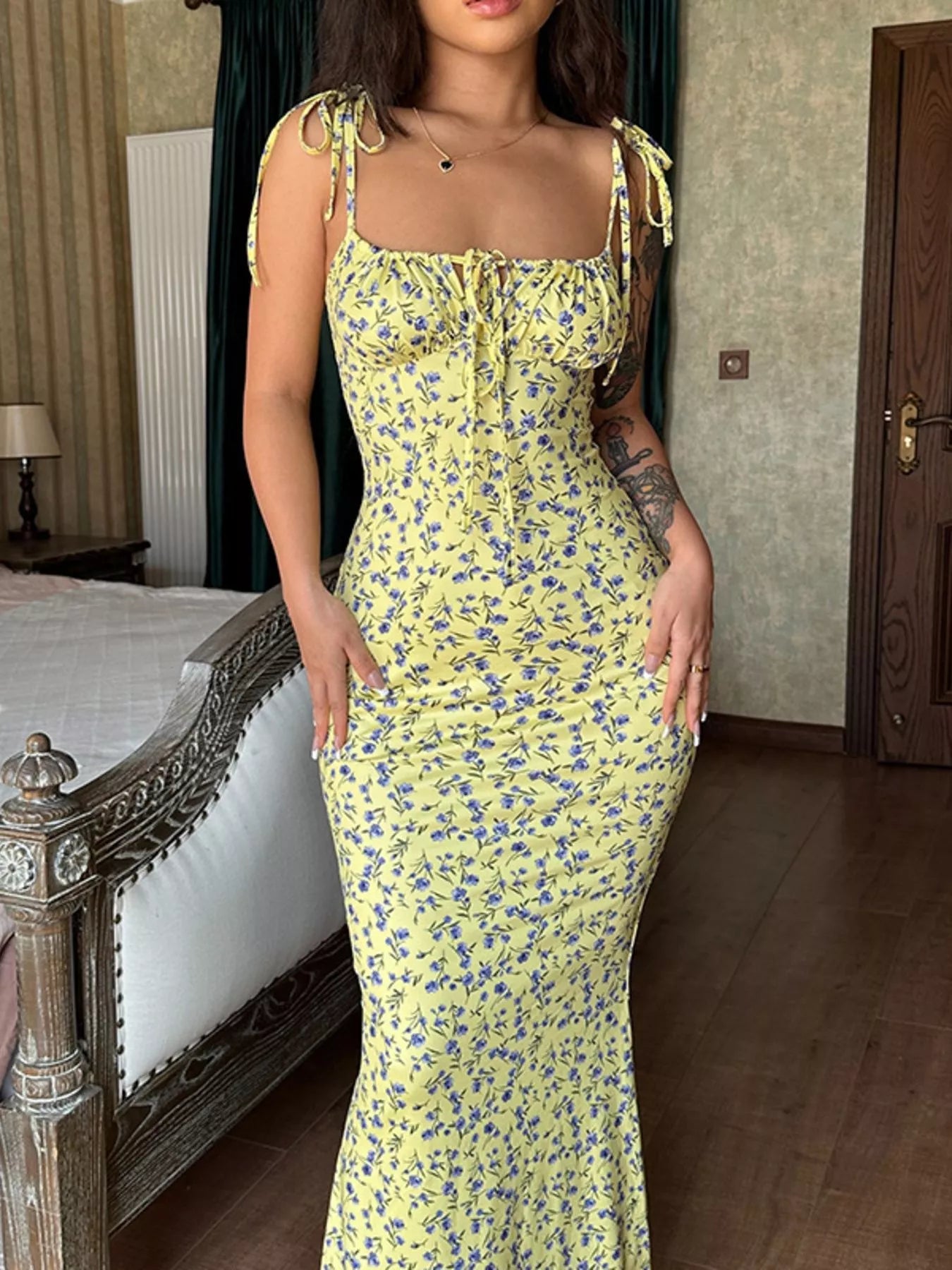 Model standing indoors in yellow floral print bodycon maxi dress with tie straps and front tie detail