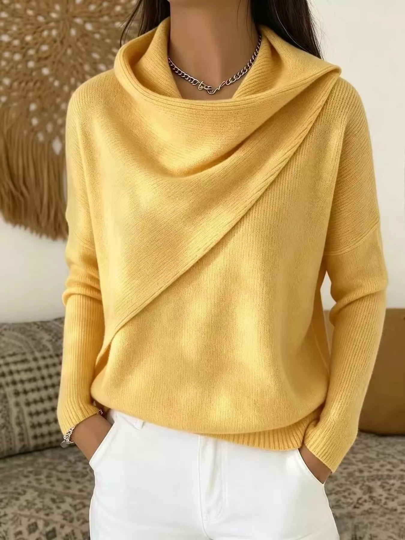 On-model front view of a yellow cowl neck sweater with a draped asymmetric collar and long sleeves