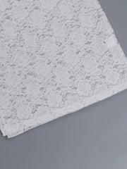 Flat detail of a white lace maxi dress skirt hem showing the floral lace pattern