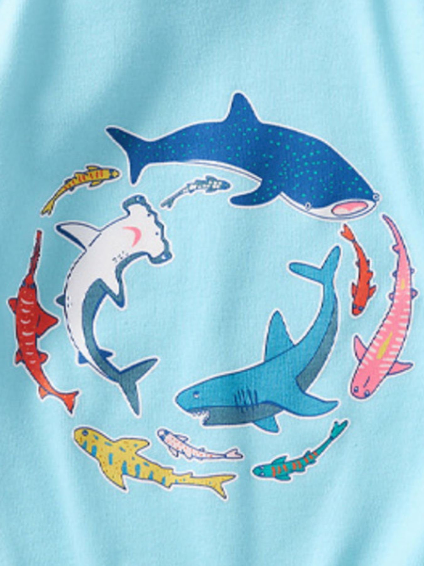 Detail view of colorful shark graphics arranged in a circle on a children's pastel blue t-shirt