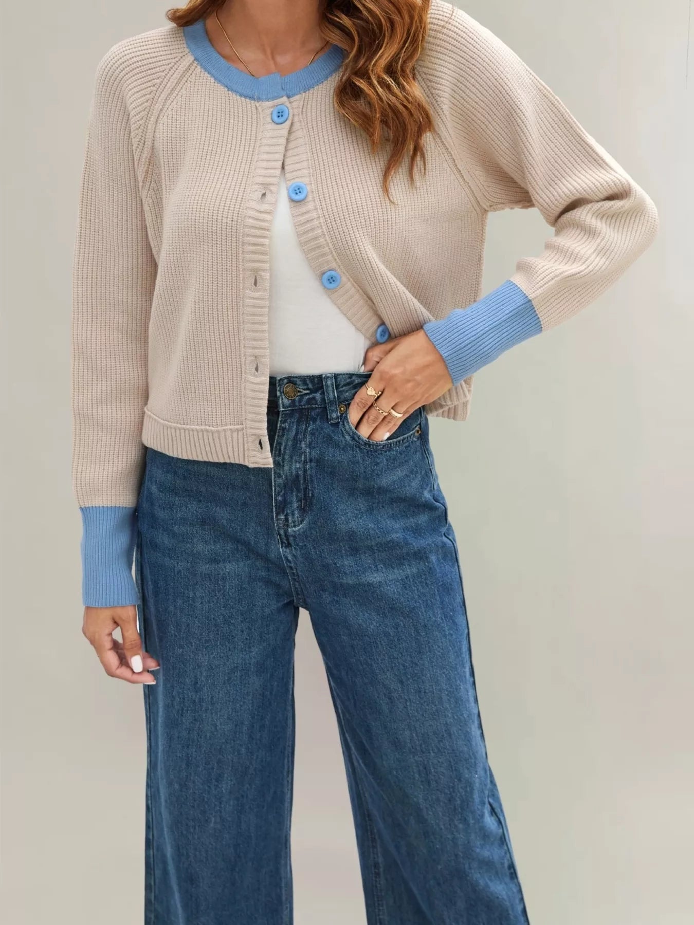 On-model front view of the beige cardigan with light blue trim worn open over a white top