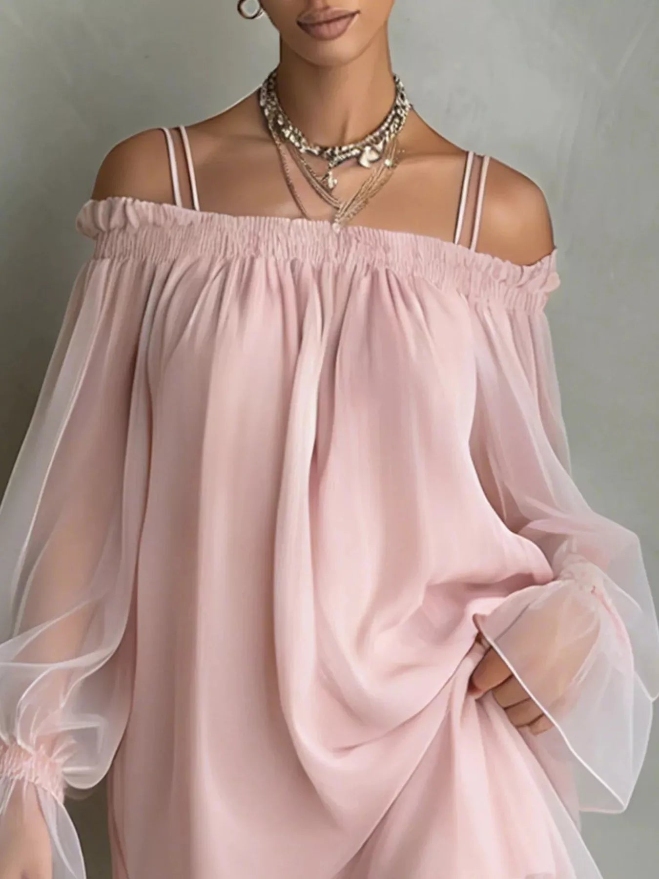Close front view of a dusty pink off shoulder dress showing the smocked neckline and sheer sleeves