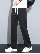 Men's black casual pants with wide legs and a drawstring waist.