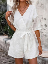 Women's white eyelet romper with a tied front and semi-sheer fabric.
