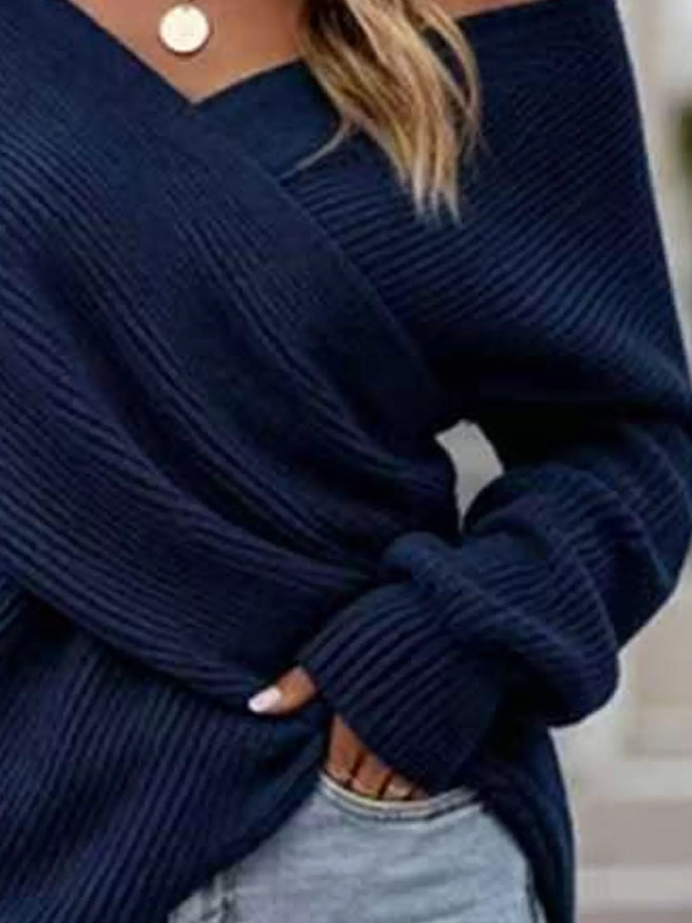 Close front view of navy blue ribbed knit sweater showing crisscross V neckline detail.